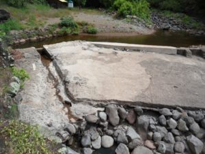 Broken concrete and large rocks block streamflow